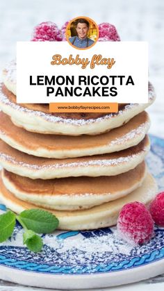 a stack of pancakes with powdered sugar on top and raspberries in the background