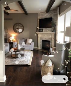 a living room filled with furniture and a clock mounted on the wall above it's fireplace