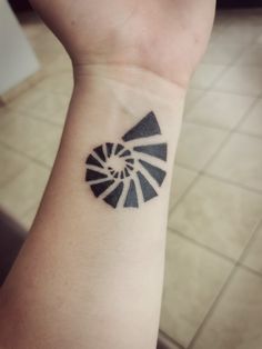 a person with a small tattoo on their wrist that has a black and white design