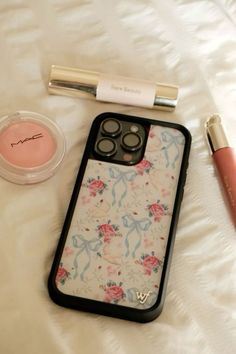 an iphone case sitting on top of a bed next to makeup