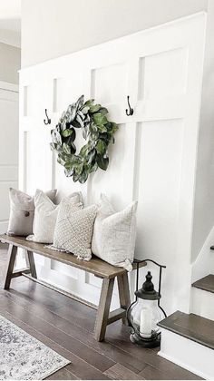 a bench with pillows and a wreath on the wall above it in front of stairs