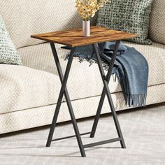 a wooden table sitting on top of a couch next to a vase with flowers in it