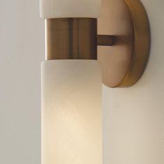 a close up of a light fixture on a wall with a white and gold finish