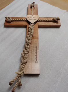 a wooden cross with rope wrapped around it and a heart on the top, sitting on a white sheet