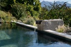 a large rock sitting next to a pool with water running from it's sides