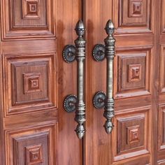 the door is made of wood and has metal handles on each side with decorative knobs