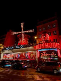 cars parked in front of a building lit up with christmas lights and a large cross