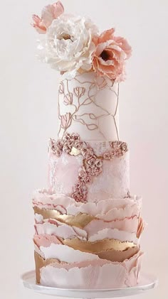 a three tiered wedding cake with pink and white flowers on the top, in front of a white background