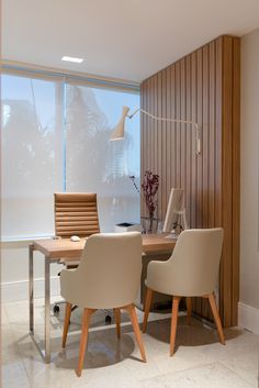 an office with two chairs and a desk in front of a large window