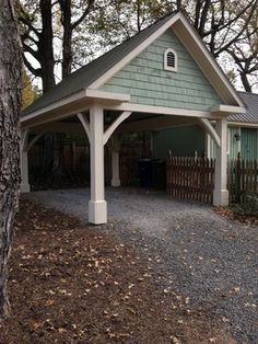 a house with a carport in the middle of some trees and gravel ground next to it