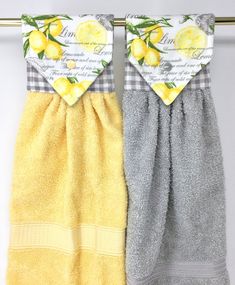 two yellow and gray towels hanging on a clothes line with lemons printed on them