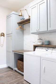 a washer and dryer in a small room with white cabinets, wood flooring