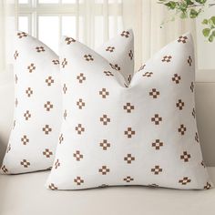 two white pillows with brown crosses on them