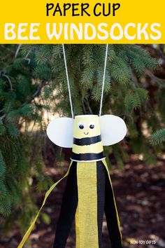 a paper cup bee wind sock hanging from a pine tree with text overlay that says paper cup bee windsocks