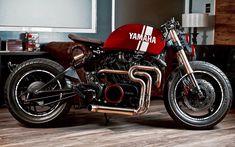 a red and black motorcycle parked on top of a hard wood floor