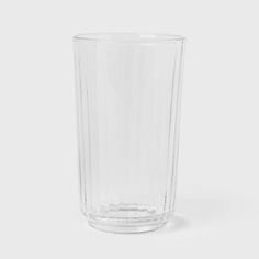 a clear glass is sitting on a white surface with the bottom half empty and no one around it