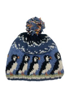 a blue and white knitted hat with penguins on the front, two pom poms