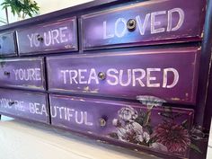 a purple dresser with flowers painted on the drawers and words that read, you're loved, you're treasures, you're beautiful