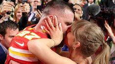 a man and woman kissing each other in front of a crowd