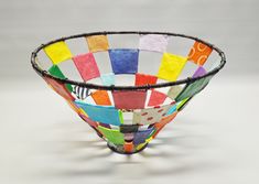 a colorful glass bowl sitting on top of a white table next to a gray wall