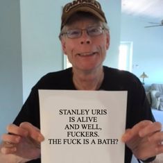 an older man holding up a sign that says stanley urris is alive and well, f