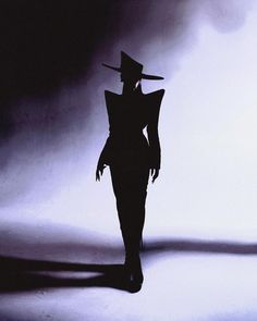 the silhouette of a woman wearing a hat and dress