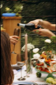 two people are toasting wine glasses at a table with flowers and candles on it