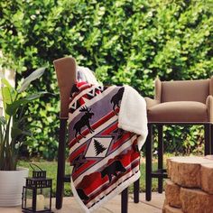 a blanket sitting on top of a wooden chair next to a fire place and potted plant