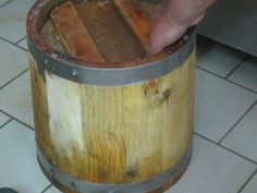 a person is holding onto a wooden barrel on the floor next to a tile floor