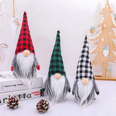 three gnome figurines sitting on top of a table next to pine cones and christmas decorations