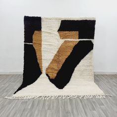 a black, brown and white rug with fringes on the floor in an empty room