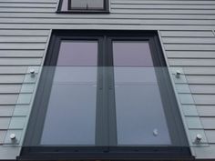 an open window on the side of a gray house with black trim and metal studs