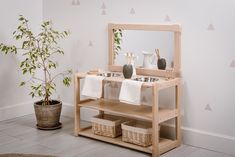 a wooden shelf with two sinks under a mirror next to a small potted plant