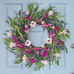 a blue door with a pink and white wreath hanging on it's front door