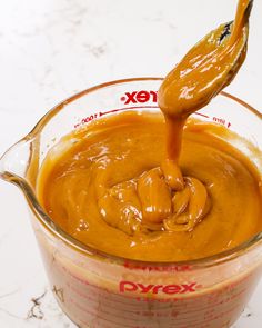 sauce being poured into a glass measuring cup