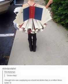 a woman in a dress made out of books is standing on the sidewalk with an umbrella