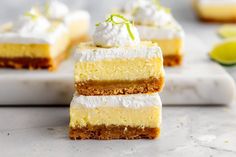 three pieces of cake sitting on top of a white cutting board next to lime slices