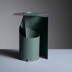 a green vase sitting on top of a table next to a gray wall and floor