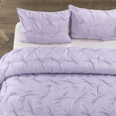 a bed with purple comforter and pillows on it