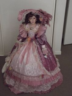 a doll is sitting on the floor in a pink dress