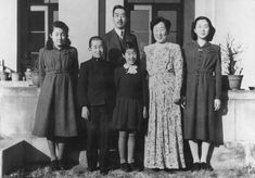 an old black and white photo of people standing in front of a house with two children