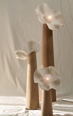 three wooden vases with lights in them on a white tableclothed surface,