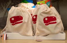 two bags with dinosaurs printed on them sitting on a table next to toothbrushes