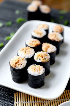 sushi is served on a white plate with chopsticks