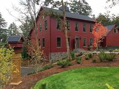 a large red house sitting on top of a lush green field next to a forest