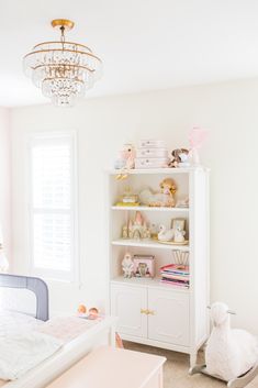 a baby's room with white furniture and pink walls