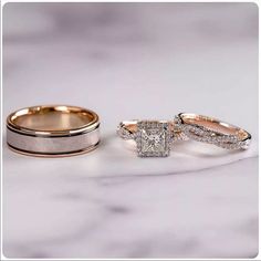 two wedding bands and one engagement ring on a marble countertop with the same diamond in between them