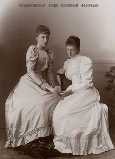 two women sitting next to each other in dresses