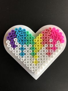 a heart made out of legos on a black surface with the colors of the rainbow