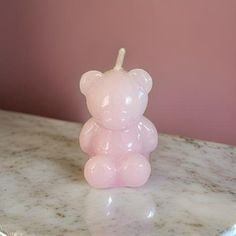 a pink teddy bear candle sitting on top of a marble table